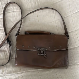 Cool väska🤎 - Brun väska med stjärnor på framsidan, ett långt löstagbart band och ett kort🤎 vet inte märket för den är köpt på secondhand🤎 inga defekter🤎