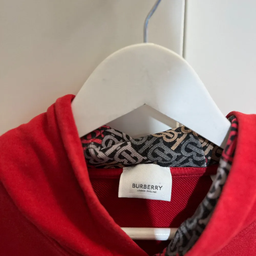 En Burberry Hoodie , i en härlig röd färg, väntar på att bli en del av din garderob! Denna klassiska och trendiga huvtröja är perfekt för att ge din outfit en touch av lyx och komfort.  Axelbred:42cm Längd: 68cm. Hoodies.