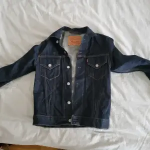 Oanvänd mörkblå Levis jeans jacka. Strl S tror att det är herr jacka då den är ganska stor, funkar perfekt för kvinnnor strl M-L. Mått rygg 43cm Längd 60cm Arm 61cm  Obs: Det går alltid att diskutera priset ; )