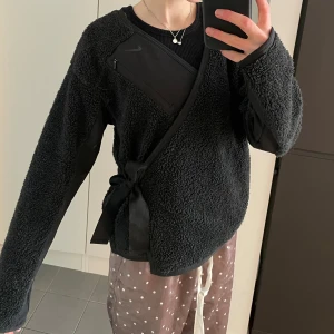 Wrap top NIKE teddy - Svarta wrap top i teddymaterial från NIKE i storlek XS men oversized. Stor och fluffig. Ok skick. Unik!