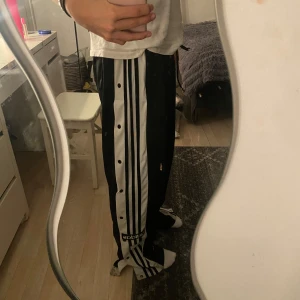 Svarta Adidasbyxor med knappar på benen - Svarta adidas byxor, köpta för ca två månader sen och använt dem lite men dem ser nya ut!