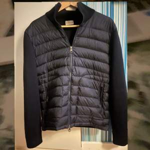 Marinblå Moncler cardigan Jackan. Är i utmärkt skick och har endast ett litet fel på klädhängaren vilket visas i sista bilden. Den är köpt för 9000 kr och jag har ett digitalt kvitto som bevis på äktheten. Priset är förhandlingsbart!