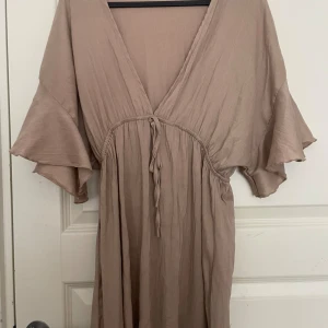Beige strandklänning klänning - Säljer denna strandklänning köpt på Sellpy för ett halvår sedan. Står varken storlek eller märke i men passar på mig som är M, så skulle säga S-M