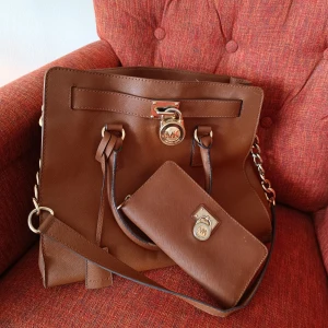 Michael Kors väska med plånbok  - Snygg väska brun  med tillhörande plånbok säljes då den inte används nypris 4800 kr   Finns lite slitage men snygg och fin 