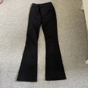 Svarta Peachy Flare byxor - Byxorna har en längd på 33 och är tillverkade i ett stretchigt material för en bekväm passform. Byxorna är bootcut. passar främst de med längre ben då de är i längd 33