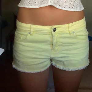 Gula jeansshorts - Ett par gula jeansshorts med fransade kanter. Shortsen har en knapp och dragkedja framtill samt fickor både fram och bak.