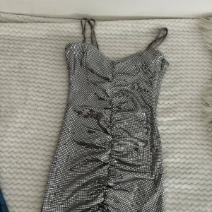 minidress  - säljer denna sexiga minidressen från Gina. köpte för ca två år sen men har endast använt vid ett tillfälle. den är i storlek S och sitter bra på en. Den är silvrig.