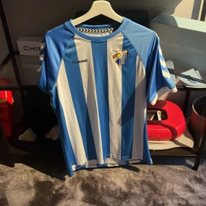 Malaga fotbollströja - Tröjan är i väldigt fint skick och är köpt på den  officiella shoppen i Malaga. Priset kan diskuteras vid snabb affär.