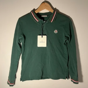 Moncler pike - Moncler pike som passar dig som är ungefär 150cm till 160cm. skick 8/10 tröjan har ett litet hål som ni kan se på bild tre men det är ihopsytt. Priset är ej hugget i sten. mvh/reselluxe
