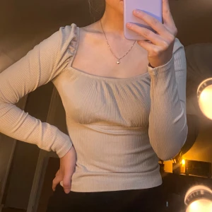 Beige topp - Beige ribbad långärmad tröja med fyrkantig urringningoch puffärmar.