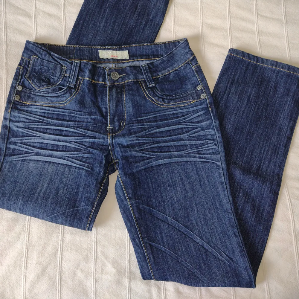 Skitsnygga y2k jeans som är raka/något utsvängda i modellen. Låg/medelhög midja. Brodyr på bakfickor och lilla fickan i fram, och en del slitningar. I fint skick. 95% bomull. Storlek 42 - innerbenslängd ca 84 cm, midja ca 40 cm mätt tvärs över.. Jeans & Byxor.