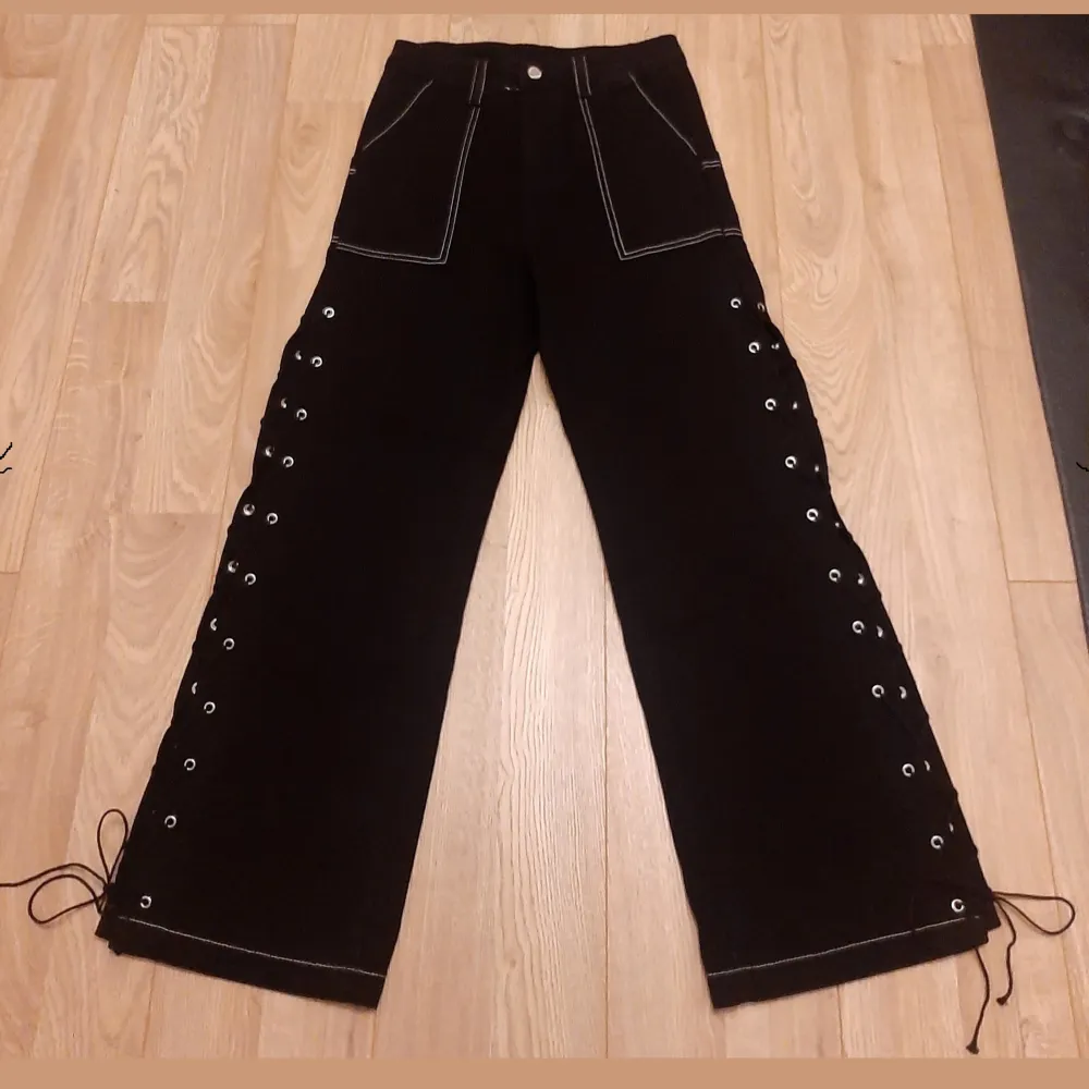 Svarta, vida baggy jeans med öppna sömmar längs benen och vit kontrastsöm. Gothstil. Varken testade eller använda. (Köpt fel storlek). Strlk: M.. Jeans & Byxor.