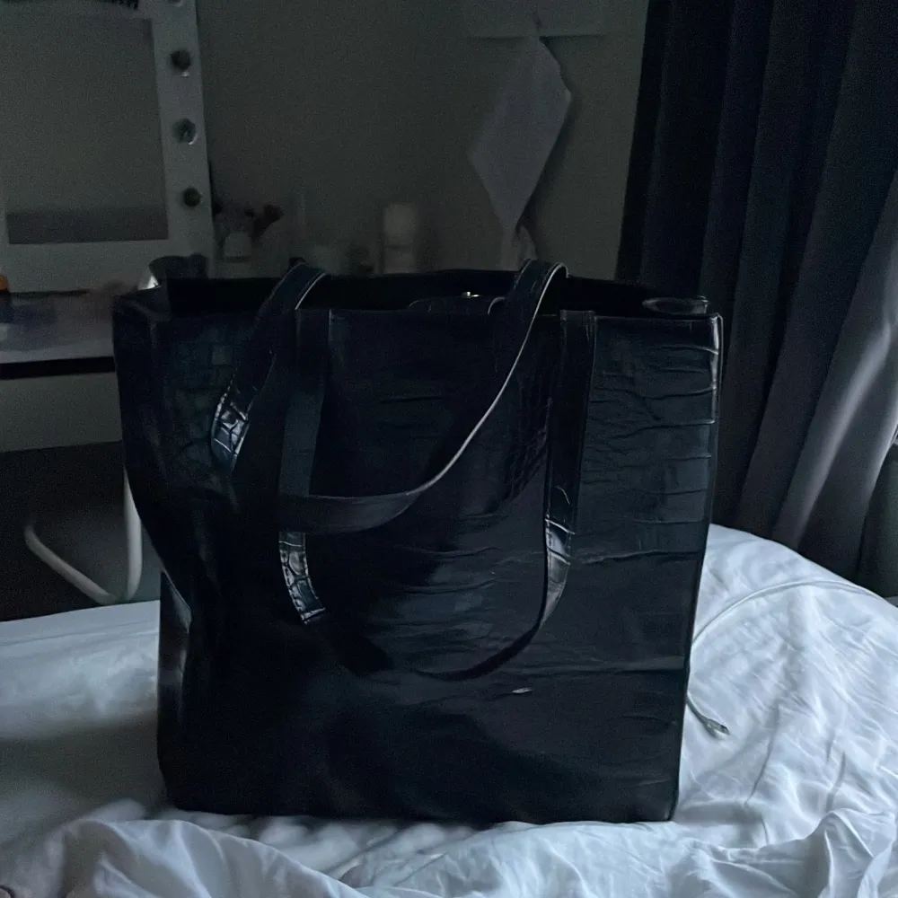 En svart väska med skin mönster . Väskor.