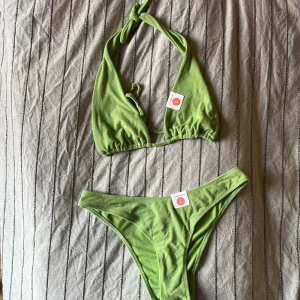 Grön bikini från Bik Bok - En grön bikini från Bik Bok i storlek L. Bikinin består av en överdel med knytband och en matchande underdel. Materialet är mjukt och stretchigt, vilket ger en bekväm passform. högt skuren underdel. frotteliknande material! 