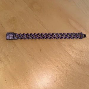 Purlple Cuban Link Armband - Material: Black Gold Plated (pläterad) Stone: Type: CZ Stone (kubisk zirkonia) Width: 15mm (bredd) Bracelet Length: 17cm Product Type: BRACELET  (armband)   Det passar inte mitt arm så jag säljer en lila cuban länk armband som är 17cm lång.