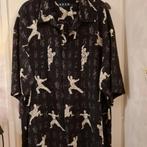 Möntrad skjorta  - Mönstrad skjorta med karategubbar på. Den är oanvänd och i väldigt bra skick. Den är i storlek xxl och är från märket Exco sport