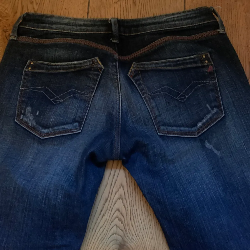 Mörkblå low waisted jeans med detaljer på bakfickan och röda detaljer vid midjan . Jeans & Byxor.