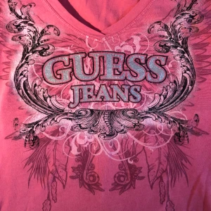 Guess topp - Snygg t-shirt från märket Guess som tyvärr inte används 💗 Storlek M men rätt så stor i storleken.  Alla defekter syns på sista bilden, ett litet hål på framsidan, och några fläckar bak.
