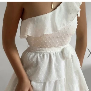 One shoulder klänning  - Så fin vit one shoulder klänning från showpo men volanger. Den är helt oanvänd och har prislappen kvar. Säljer den då jag tyvärr inte fått användning av den ännu. Storlek 34. Köparen står för frakten.