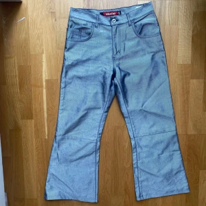 Smog glansiga baggy jeans - Baggy jeans från märket Smog i silvrig färg som var en hit på 90talet! Fet passform, säljer pga av att dem inte passar.. Mått: Midja: 38cm Ytterben: 93 Benöppning: 27.5