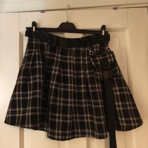 Svart minikjol med skärp - Svart minikjol med tillhörande skärp (går att ta av) Har en dragkedja på ena sidan, samt en ficka som av avtagbar på framsidan. Storlek L men är lite tight i midjan då den inte har stretch, passar fortfarande bra om man har den högt i midjan.