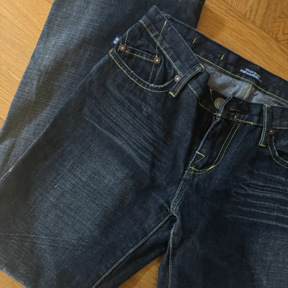 Mörkblå Flare jeans med gula sömmar och coola fickor. Mått: Midja rakt över 40cm. Innerbenslängd 70cm. Skulle säga storlek S.. Jeans & Byxor.