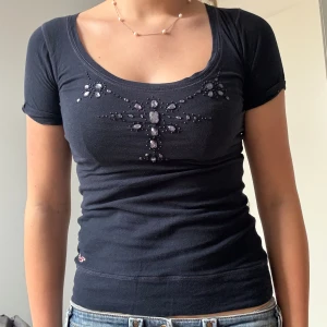 Blå t-shirt från Hollister - Marinblå kortärmad topp från Hollister med dekoration/stenar fram.