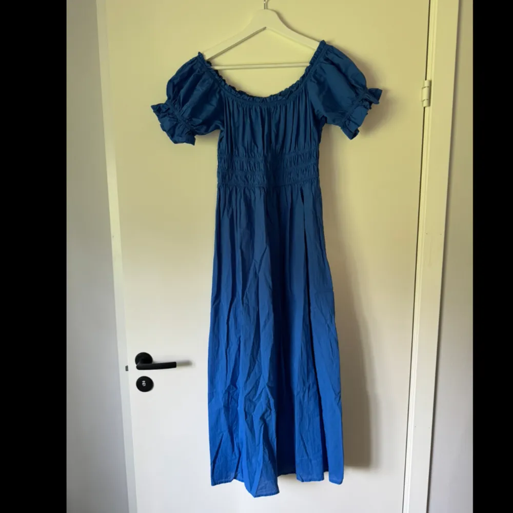 En klarblå klänning med volangen som är midi/maxi lång. Går att ha både med fyrkantig urringning eller off shoulder. Nästan aldrig använd, jättefint skick. . Klänningar.
