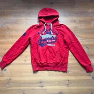 retro hoodie  - Vintage hoodie från Superdry i rött med märke både på framsidan och ärmen, skitsnygg! Säljer pga lite för stor. 