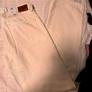 Vita jeansbyxor från 157 - Ett par vita jeansbyxor från märket 157. Byxorna har en klassisk femficksdesign och är tillverkade i ett slitstarkt material. De har en hög midja och en rak passform.