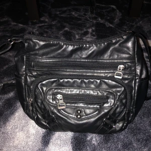 Svart axelväska i skinn - En svart axelväska i faux skinn med flera dragkedjeförsedda fack. Väskan har en justerbar axelrem och är rymlig med praktiska förvaringsmöjligheter. Skriv bara om man vill ha fler bilder eller frågor <3