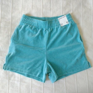 Blå mjuka shorts - storlek S - Mjuka oanvända shorts. Resår och dragsko i midjan, ficka och liten slits i sidorna. Storlek S. 83% bomull och 17% polyester. 