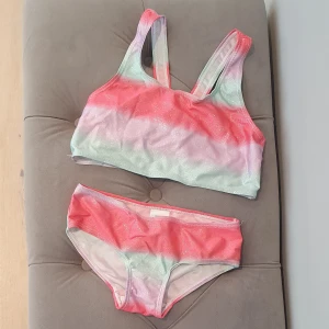 Glittrig pastellfärgad bikini 134/140 och 122/128 - Glittrig bikini i fint skick. 134/140 överdel - underdel 122/128