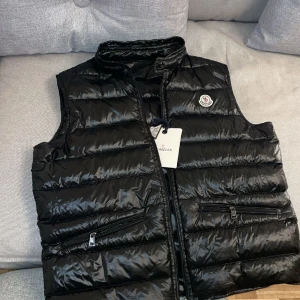 Moncler Väst GUI - Säljer min Moncler GUI väst billigt. Liten skada som man aldrig ser. Fick leta efter den för att ta bilden.