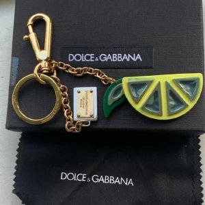 Dolce Gabbana Nyckelring/väsksmycke - Bara öppnad och tittad på, ligger oanvänd i sin originalkartong med rengöringstrasa.  Glittrar otroligt vackert i solen och passar dig lika bra som en nyckelring som ett väsksmycke. Nypriset på denna modell ligger på runt 1500-2000kr 