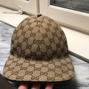 Gucci keps beige - Hej, jag säljer min äkta gucci keps beige i storlek S, kepsen är i ett toppen skick och den har inga skador. Kvitto och box följer med!
