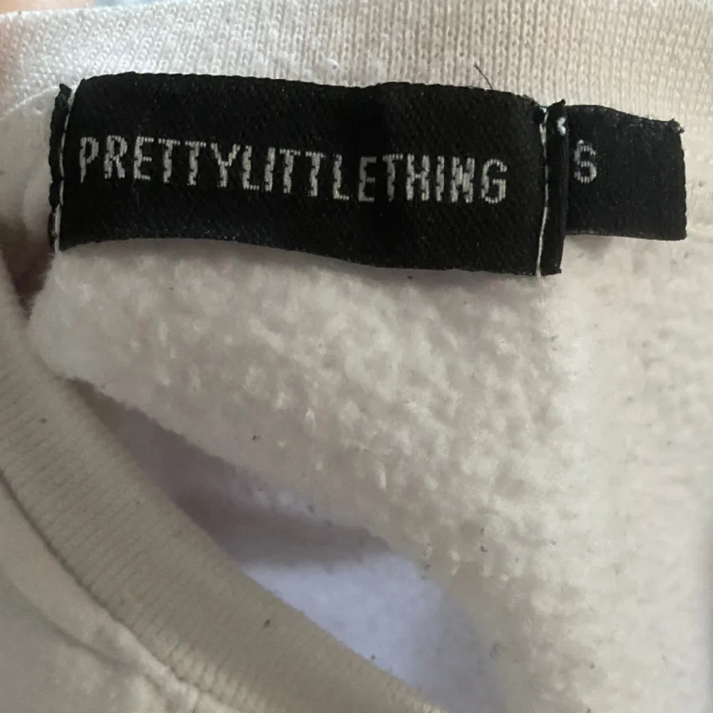 Vit sweatshirt med tryck från Prettylittlething, säljer pga att den inte kommer till någon användning . Tröjor & Koftor.