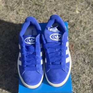 Adidas skor - Jättefina HELT SLUTSÅLDA adidas campus 00 skor som jag aldrig använt. Färgen är klarblå och storleken är 37. Man får med vita tjocka snören, vita smala, blå tjocka och blå smala. Kartongen följer också med.