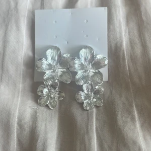Blommiga örhängen  - Säljer dessa jättefina blommörhängen, köpta här på plick och helt oanvända (tidigare ägare har heller ej användt dom) säljer då jag använder mer guld. 