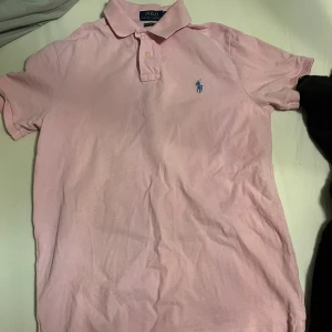 Ralph Lauren piké - Fin rosa piké t shirt i rosa storlek S. Det finns små små fläckar som man ser ifall man kollar riktigt noga eller zoomar in. Inget slitage eller annat finns på den, vid andra frågor skriv gärna privat  Nypris ligger på 1500. Pris kan diskuteras.
