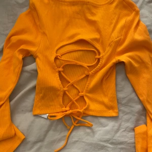 tröja med öppen rygg - Fin orange topp med snördetalj i ryggen, perfekt till sommaren. Strl M. Ser ut som produktbilderna på bara de att de är en annan färg. Aldrig använd.
