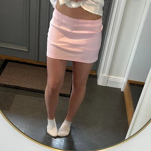 Rosa lågmidjad kjol  - Ljusrosa lågmidjad kjol från Vero Moda. Står storlek 38 men jag har sytt upp den från en lite mer högmidjad kjol så jag skulle säga S/M. 36 cm + stretch tvärs över midjan och 31 cm längs med sidan. Materialet liknar jeans. Använd gärna köp nu!