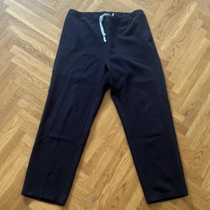 Svarta byxor från Weekday - Ett par svarta byxor från Weekday i storlek L. Byxorna har en elastisk midja med dragsko för justering.