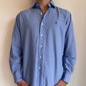 Ralph Lauren - Blårutig Ralph Lauren skjorta i storlek 15,5 vilket motsvara ca L. Skjortan är i fint skick utan några skavanker. Modellen är 186 cm lång. Orginalpris ca 1500 kr och nu endast 499. 