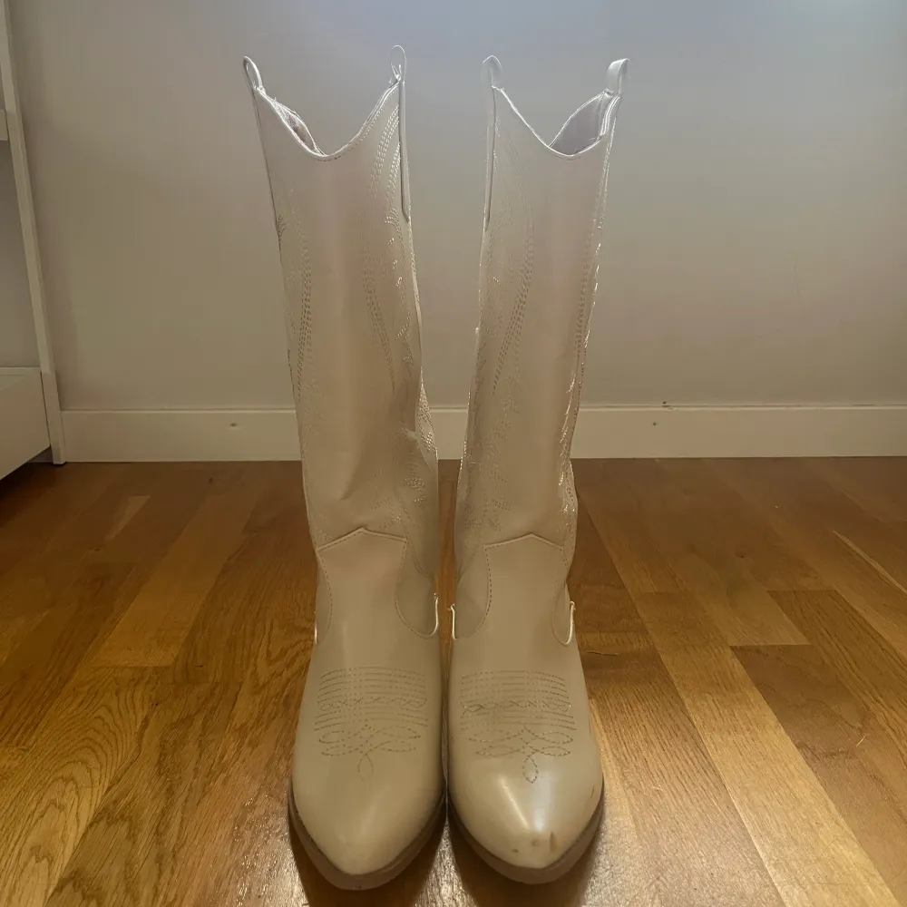 Cowboy boots köpta på bohoo. Använda 1 gång på konsert. Fläckarna på skon va där när jag fick dom. Lite skav längst fram på skon. Annars i bra skick. Skon är mer naturvit. Köpta för ca 450 kr.. Skor.