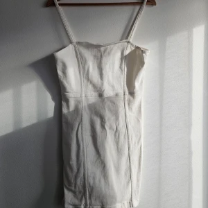 Vit klänning  - Säljer en stilren och elegant vit klänning.Perfekt för sommardagar och speciella tillfällen. Klänningen är figursydd för att framhäva din siluett på ett smickrande sätt. Perfekt för både vardag och fest.Endast använd en gång. 