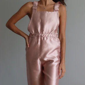 Unik jumpsuit i rosa färg, strl M -  En unik jumpsuit  i storlek M från en botique shop i Sydafrika. Helt oanvänd! Storleken är M men jag bär i vanliga fall storlek S och jag skulle säga att den är mer storlek S än M. 