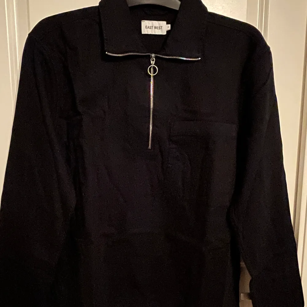 Långärmad piké-tröja i mörkblå med dragkedja upptill samt en större bröstficka på vänster sida. Aldrig använd.. Tröjor & Koftor.
