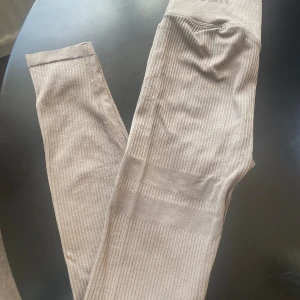 Träningstights Stronger - Träningstights i fint skicka från märket Stronger. OBS är mörkare än på bilden, lattebruna. Ribbade med hög midja.