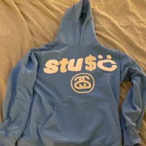 Blå Stussy hoodie, med fett tryck fram och bak 